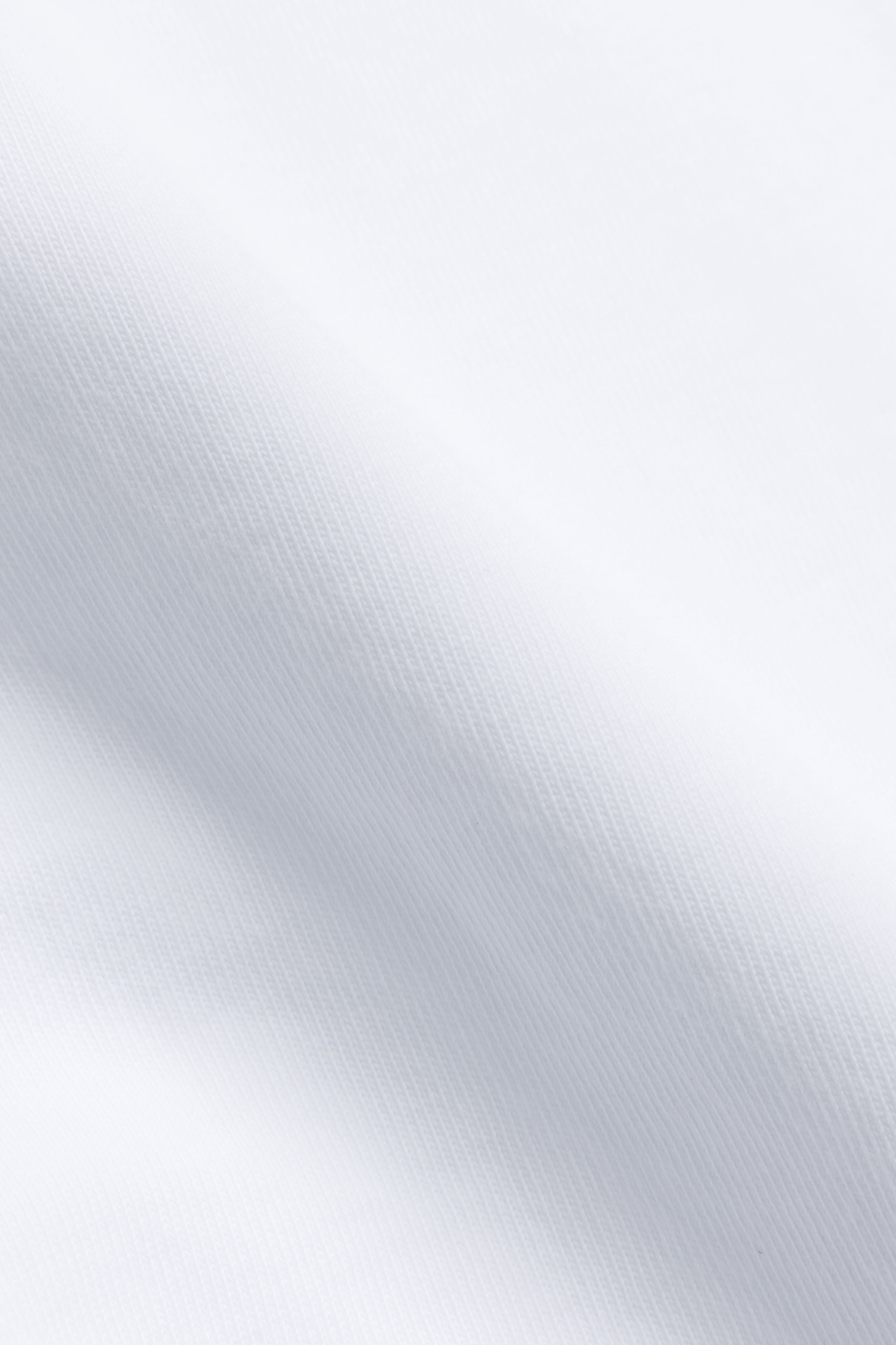Close-up of the white cotton fabric texture on a CASPARA CS Signature Tee.